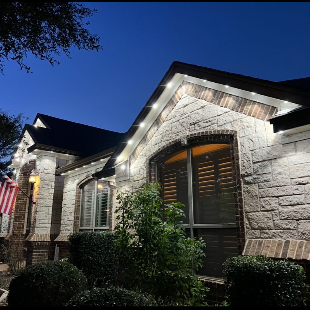 Stone home at dusk with clean white permanent LED lights tracing the eaves and gables
