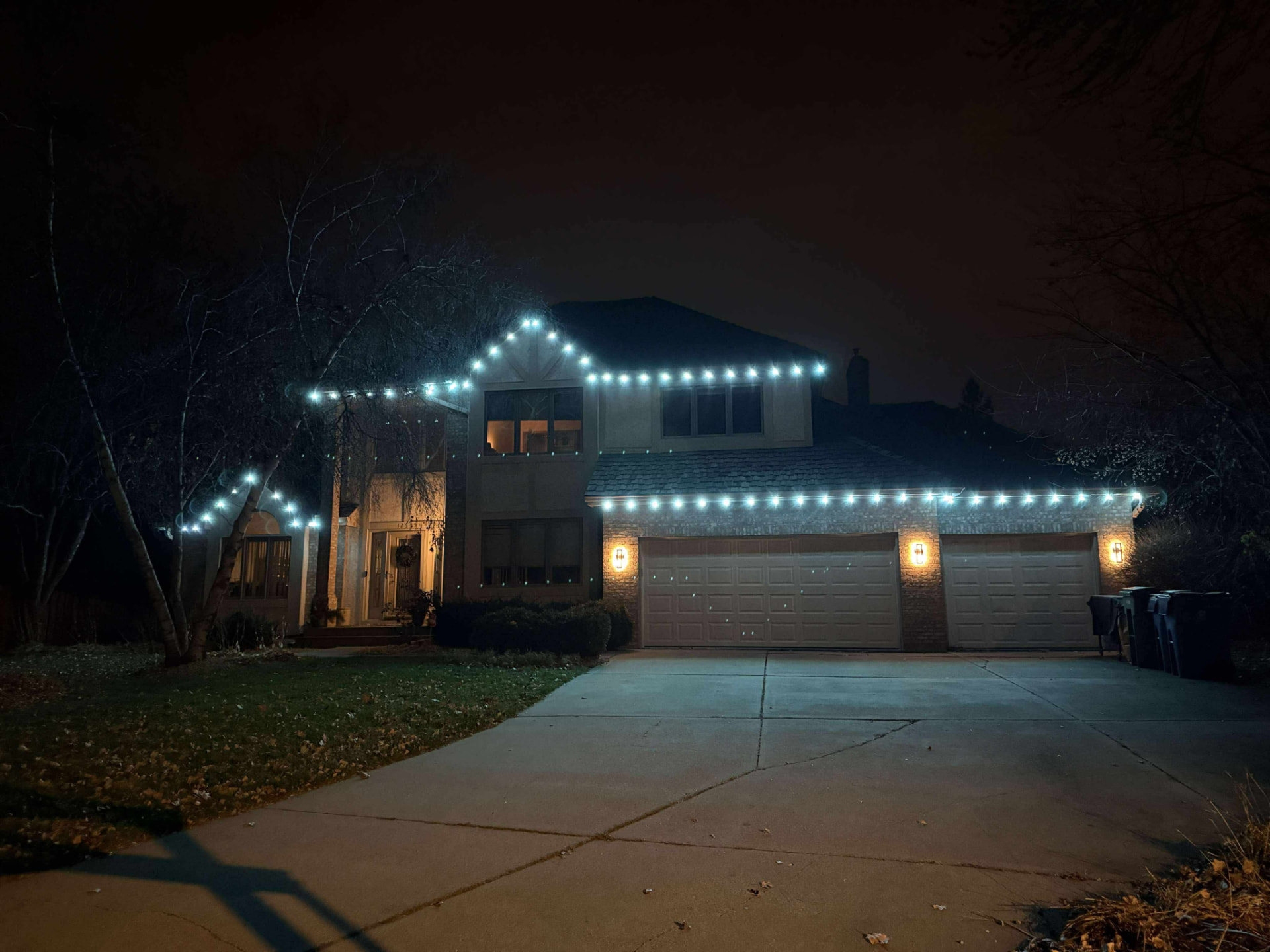 Large home outlined in crisp cool-white permanent LED roofline lighting at night