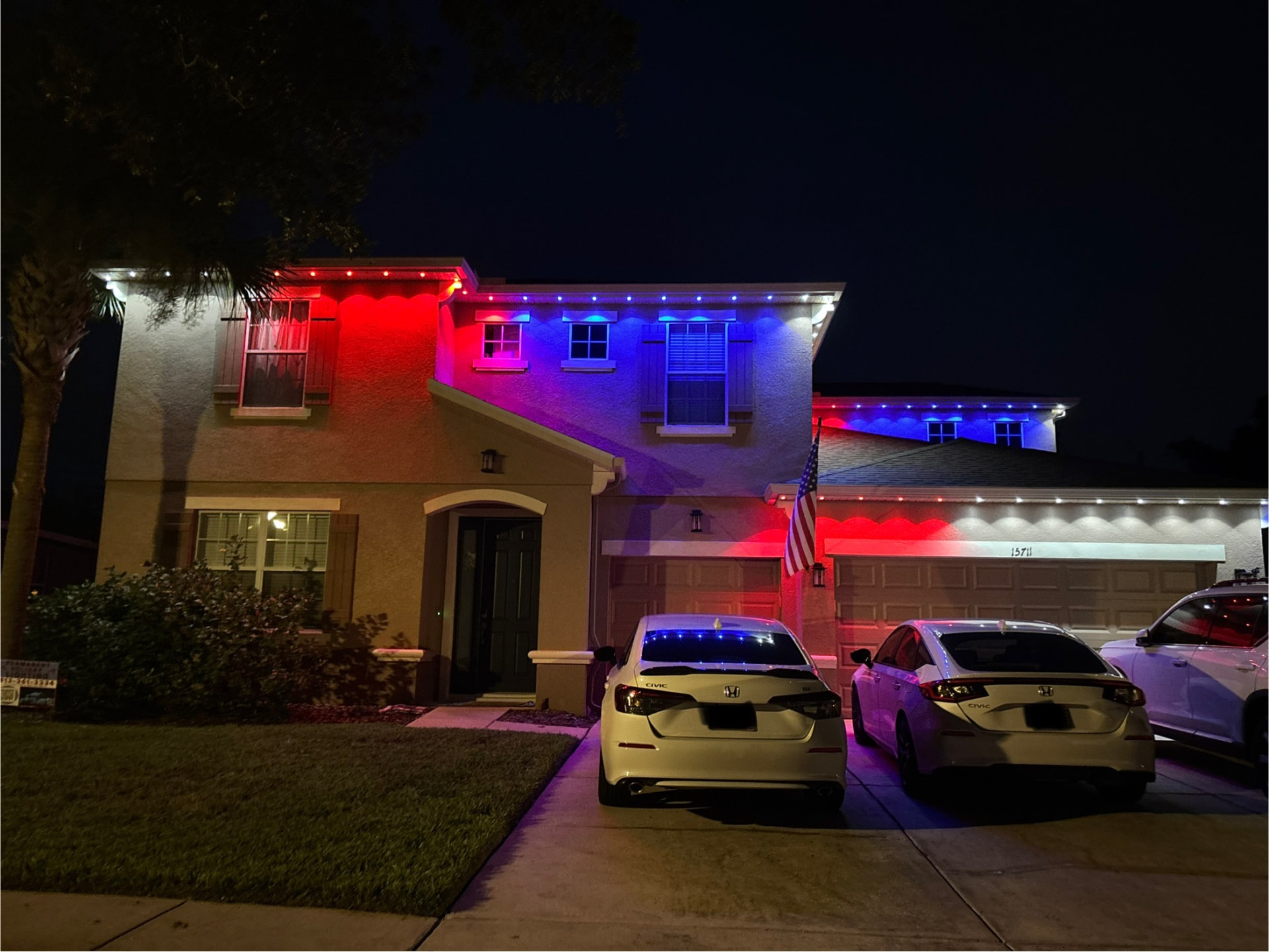 Two-story home lit in red, white and blue permanent LED lighting across the front elevation
